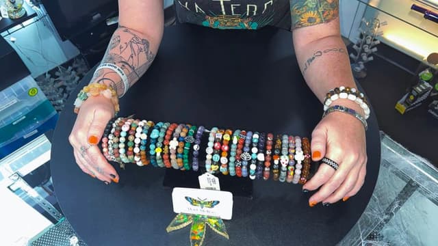A long row of handmade Mad Mellow crystal bracelets on a black display bar, ready for a pop-up